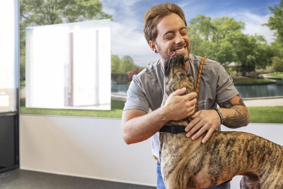 Dogtopia worker hugging a dog and getting licked