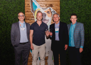 Two Dogtopia franchisees holding Dogtopia award next to Neil Gill and Jeff Farnell.