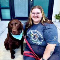 McKinnah Broussard, Assistant General Manager of Dogtopia of Downtown Orlando, with a dog.